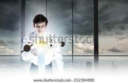 Young businessman looking on table and planets of space spinning around