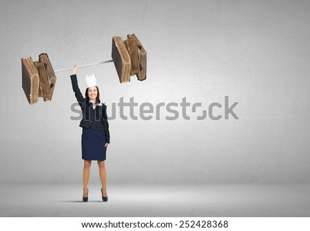 Young businesswoman in paper crown lifting books above head