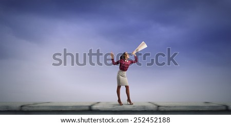 Young pretty woman screaming in paper trumpet