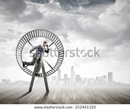 Young businessman running in huge hamster wheel