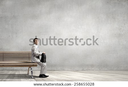 Businessman in white suit with briefcase sitting on bench