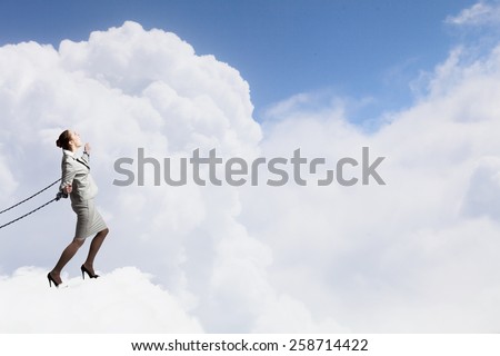 Young businesswoman with ropes on hands trying to fly