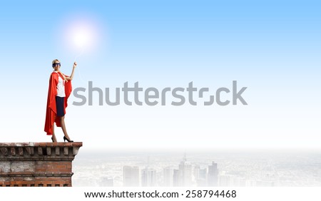 Young woman in super hero costume with bulb balloon in hand