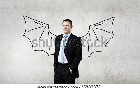 Young businessman with drawn bat wings behind back