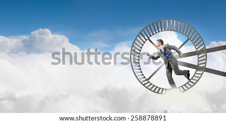 Young businessman running in huge hamster wheel