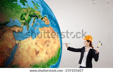 Woman builder hitting nail with hammer in Earth planet. Elements of this image are furnished by NASA