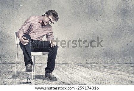 Big guy sitting on chair and stepping with foot on small one