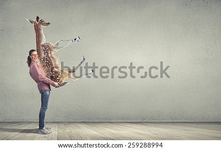 Funny young girl making effort to carry deer