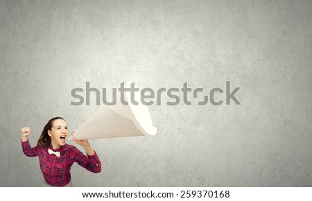 Young pretty woman screaming in paper trumpet