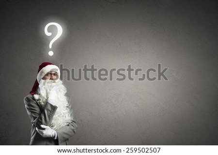 Thoughtful businessman in Santa hat with hand on chin