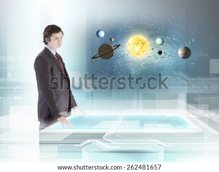 Young businessman looking on table and planets of space spinning around