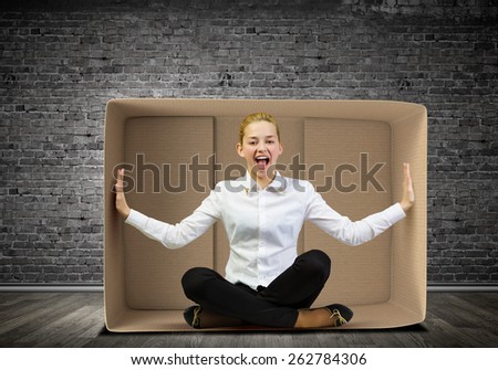 Young businesswoman sitting in carton box and feeling uncomfortable