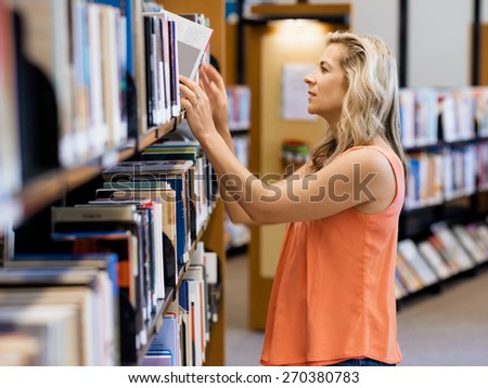 Woman picking a book in public library