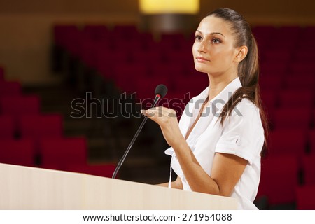 Businesswoman standing on stage and reporting for audience