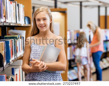 Teenage girl picking a book in public library