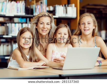 Little girls and their mum with a laptop in library