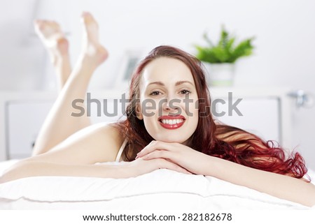 Young happy woman lying in bed and smiling