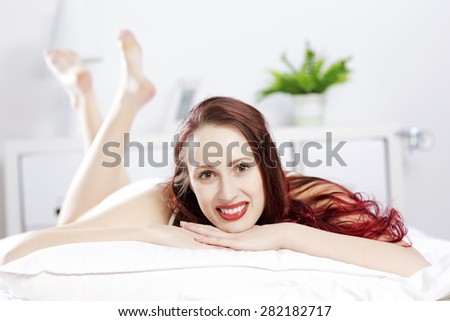 Young happy woman lying in bed and smiling