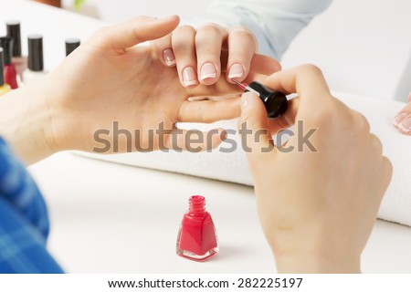 Woman in nail salon receiving manicure by beautician