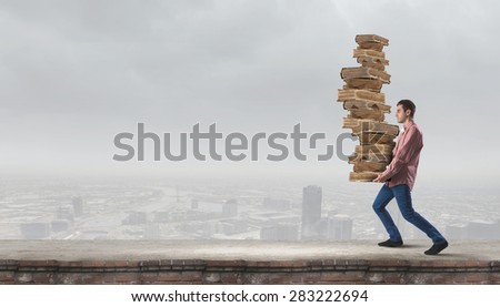 Young guy carrying pile of old books