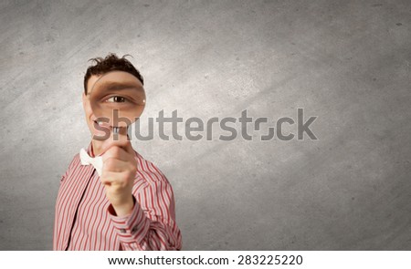 Funny image of young man looking in magnifying glass