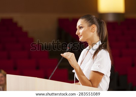Businesswoman standing on stage and reporting for audience