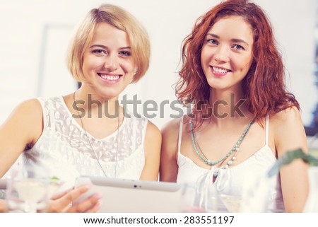 Two pretty female friends meeting in cafe