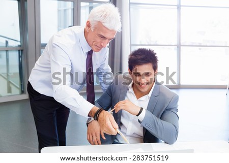Two businessman in office having discussion in front of computer