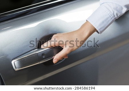 Close up of human hand opening door of car