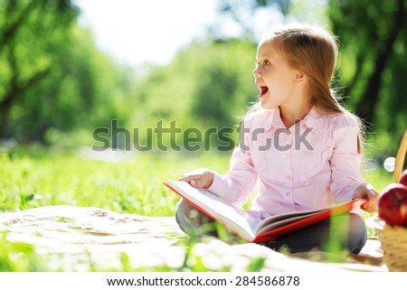 Child with book having picnic in summer park