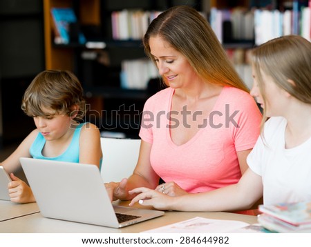 Mother with kids in library with notebook