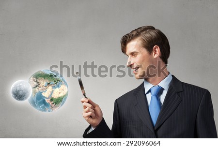 Young smiling man looking in magnifying glass. Elements of this image are furnished by NASA