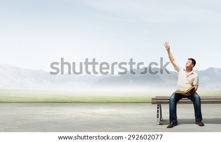 Fat man sitting on bench with book and reaching hand