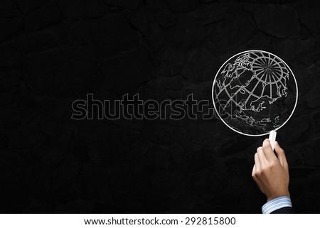 Close up of hand drawing globe on blackboard