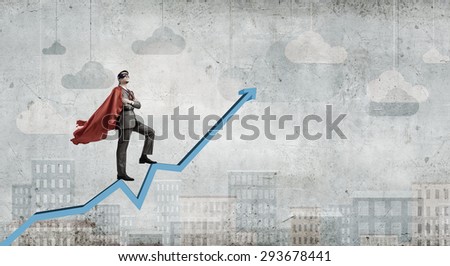 Young man in super hero costume standing on increasing graph