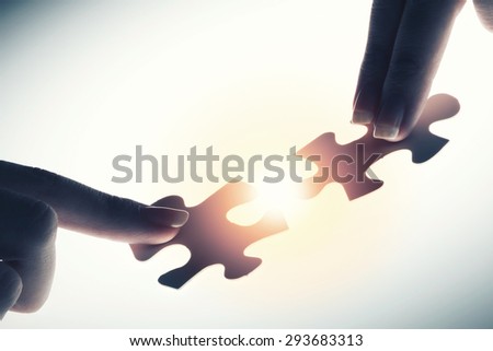 Close up of hands connecting puzzle element and making jigsaw complete