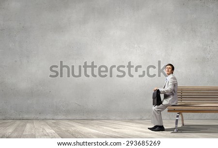 Businessman in white suit with briefcase sitting on bench