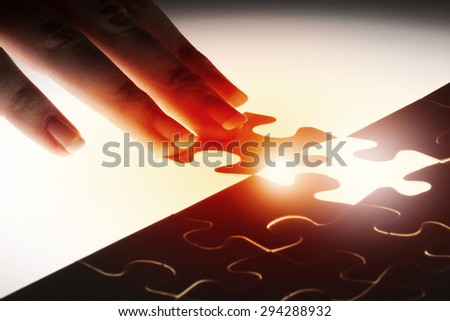 Close up of hands connecting puzzle element and making jigsaw complete