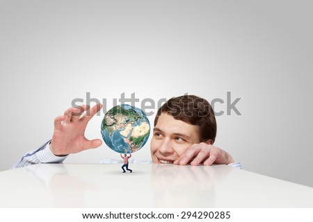 Young man looking from under table on student carrying globe. Elements of this image are furnished by NASA