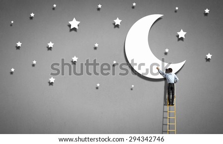 Rear view of man standing on ladder and reaching moon