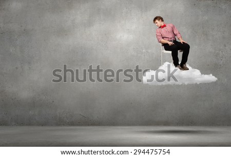 Troubled young man sitting in chair on cloud