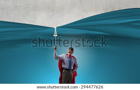 Young man in hero costume pulling blank banner from above