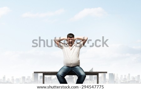 Fat man sitting on bench closing ears with hands