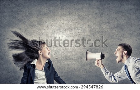 Young furious woman screaming agressively in megaphone