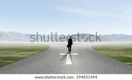 Back view of businessman standing at crossroads and making choice