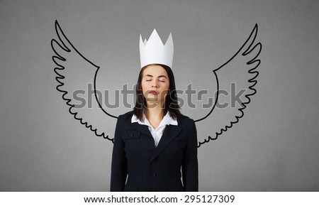 Young businesswoman in crown and with drawn wings behind back