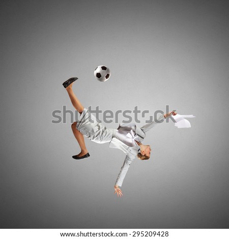Full length businesswoman in jump kicking a soccer ball
