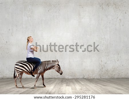 Young pretty fearless woman riding zebra animal