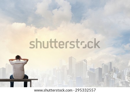 Fat man sitting on bench with his back and looking away
