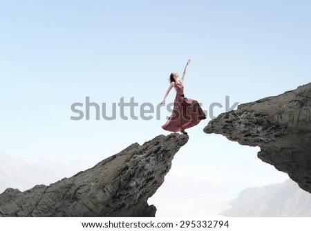 Young woman in evening dress walking over mountain gap